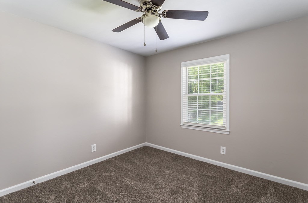 an empty room with a ceiling fan and a window
