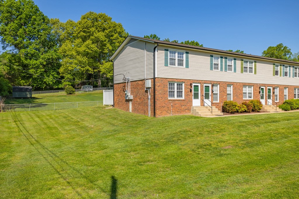 a house on a hill with a lawn and a tennis court