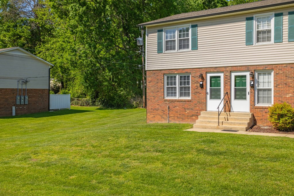 a white house with green doors and a grassy yard