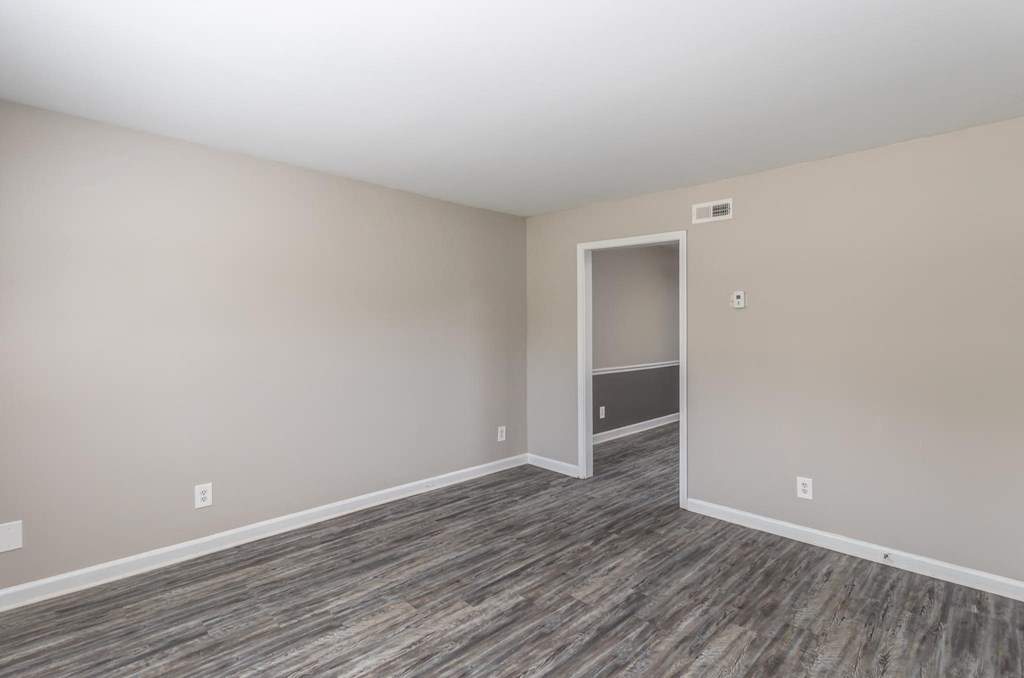 an empty living room with wood flooring and a door to a closet