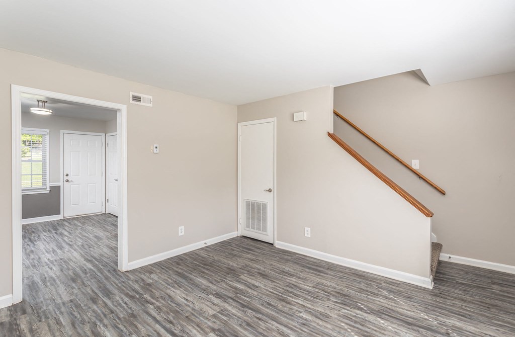 the living room and entryway of an empty house with wood flooring