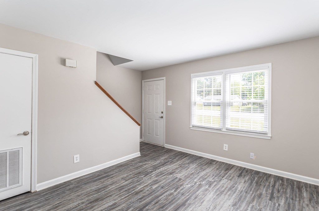 an empty living room with a window and a door