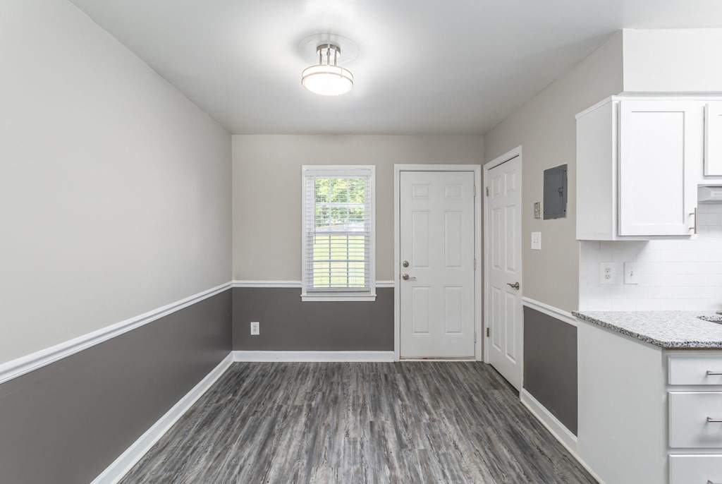 an empty kitchen with white cabinets and a window