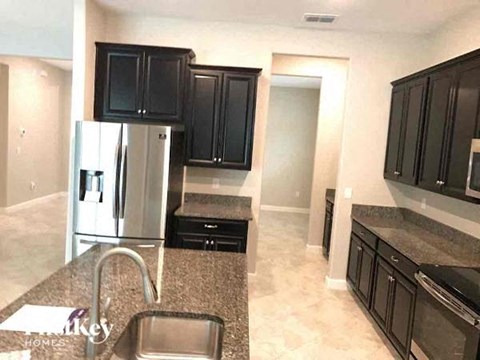 a kitchen with black cabinets and a stainless steel refrigerator