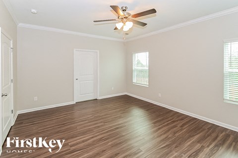 the spacious living room with hardwood flooring and a ceiling fan