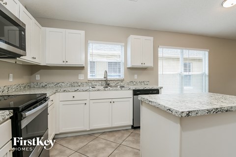 a kitchen with white cabinets and granite counter tops