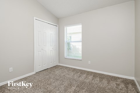 a bedroom with carpet and a door and a window