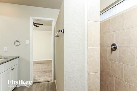 A bathroom with a shower and a doorway leading to a bedroom.