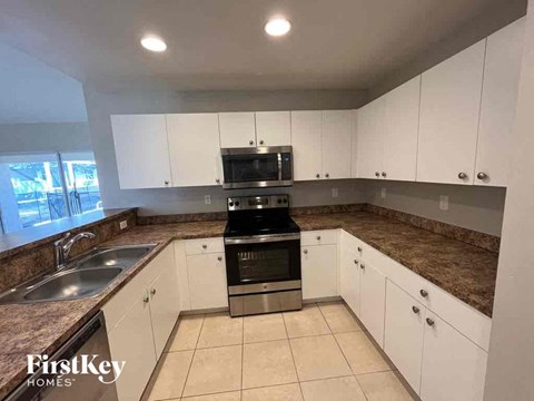 A kitchen with white cabinets and a granite countertop.