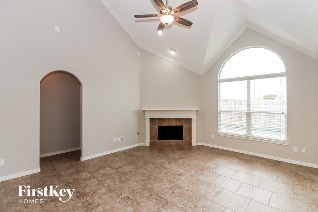 an empty living room with a fireplace and a ceiling fan