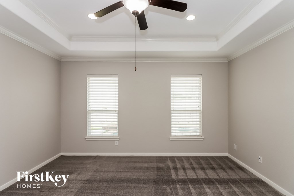 a empty room with a ceiling fan and two windows