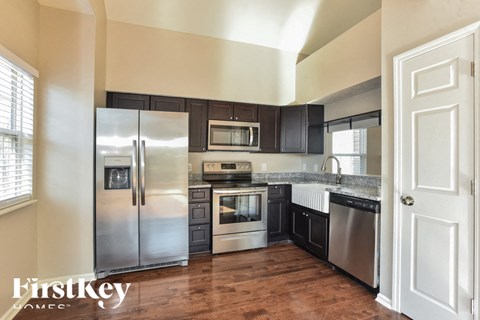 A kitchen with a refrigerator, microwave, oven, and sink.