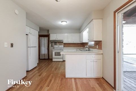 a kitchen with white cabinets and white appliances and wood flooring