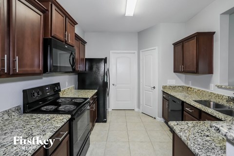 A kitchen with granite countertops and a black refrigerator.