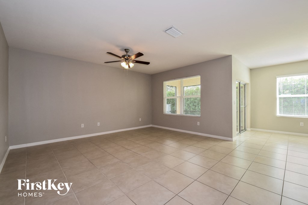 a empty living room with a ceiling fan and a tiled floor