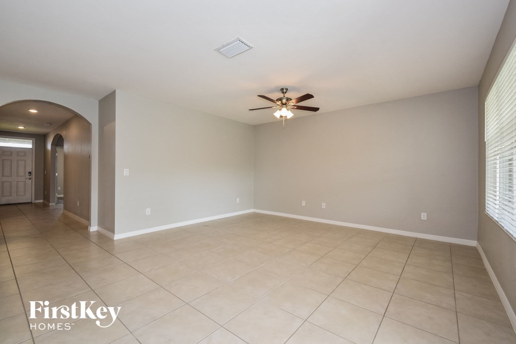 an empty living room with a ceiling fan and a tiled floor