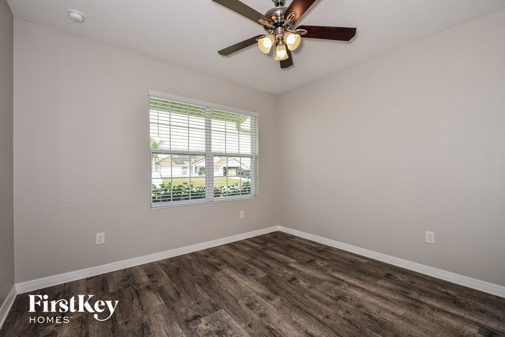 the spacious living room with wood flooring and a ceiling fan