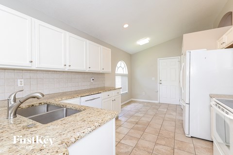 A kitchen with white cabinets and a granite countertop.