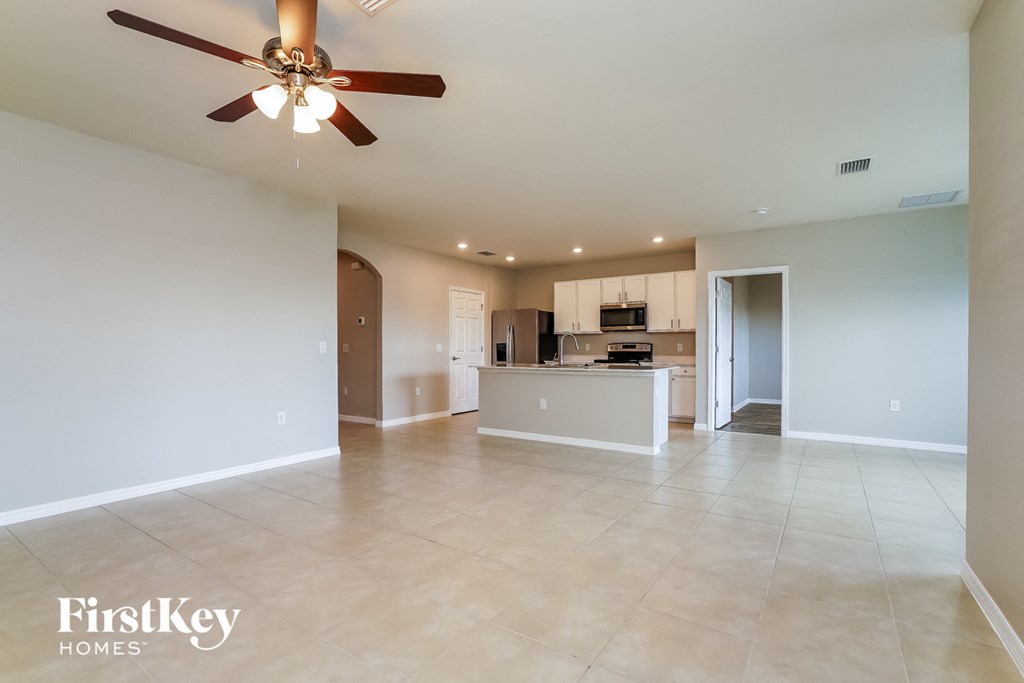 an empty living room and kitchen with a ceiling fan