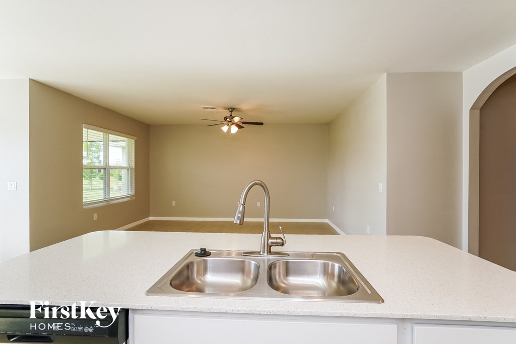an empty kitchen with a sink and a ceiling fan