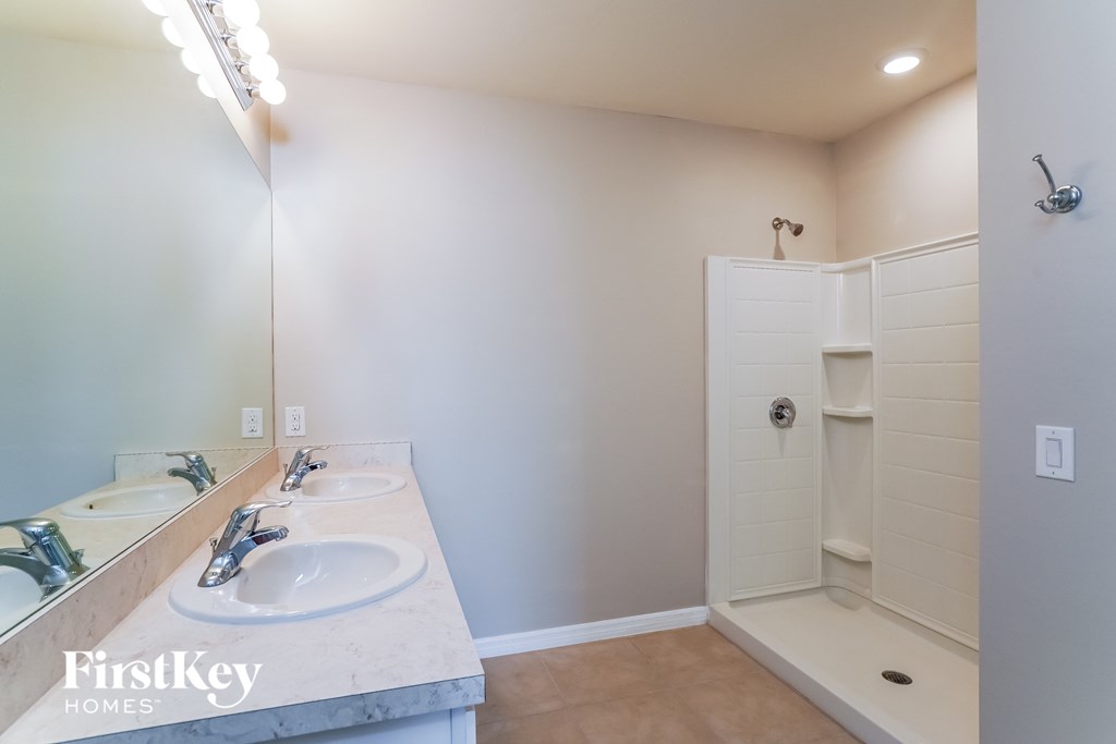 a bathroom with two sinks and a shower and a mirror