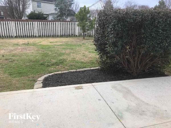 a yard with a bush and a white fence