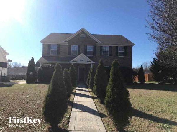 a house with a sidewalk and trees in front of it