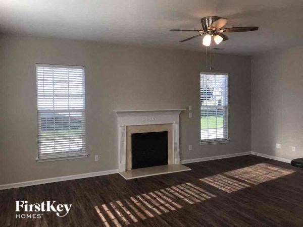 an empty living room with a fireplace and a ceiling fan