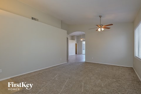 a spacious living room with white walls and a ceiling fan