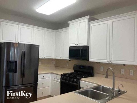 A kitchen with white cabinets and a FirstKey Homes logo.