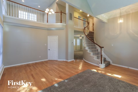 the foyer and living room of a home with a staircase and wood flooring