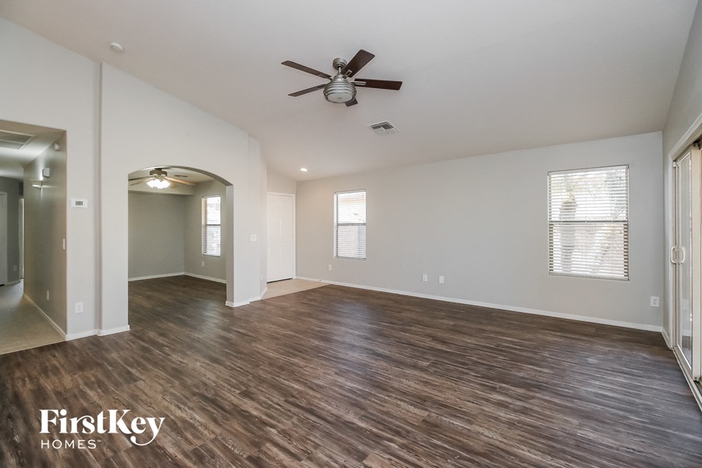 A spacious room with wood flooring and a ceiling fan.