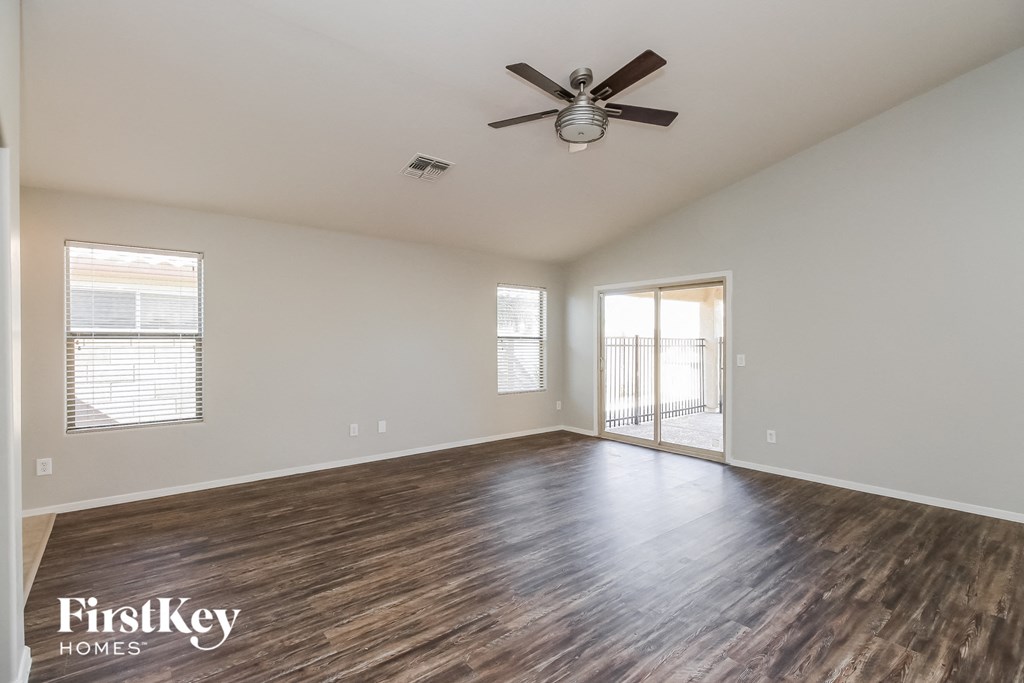 A spacious room with wooden flooring and a ceiling fan.