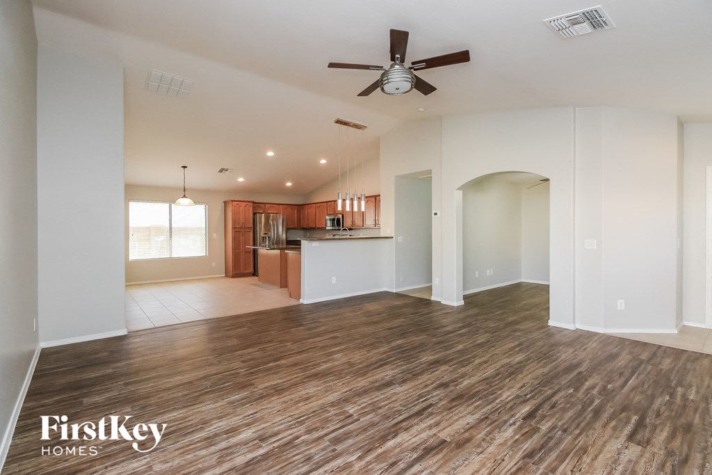 A spacious room with wooden flooring and a ceiling fan.