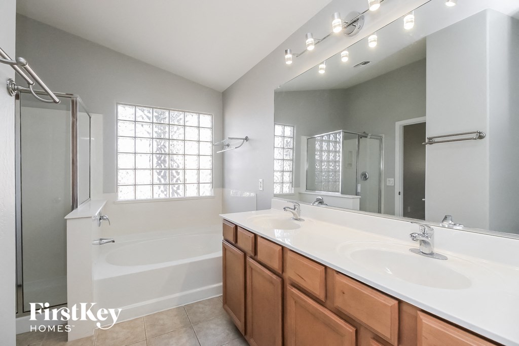 A bathroom with a tub, sink, mirror, and lights.