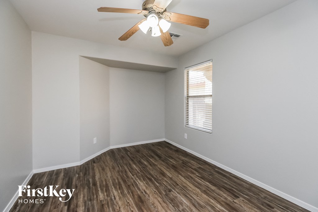 A room with a ceiling fan and wooden flooring.