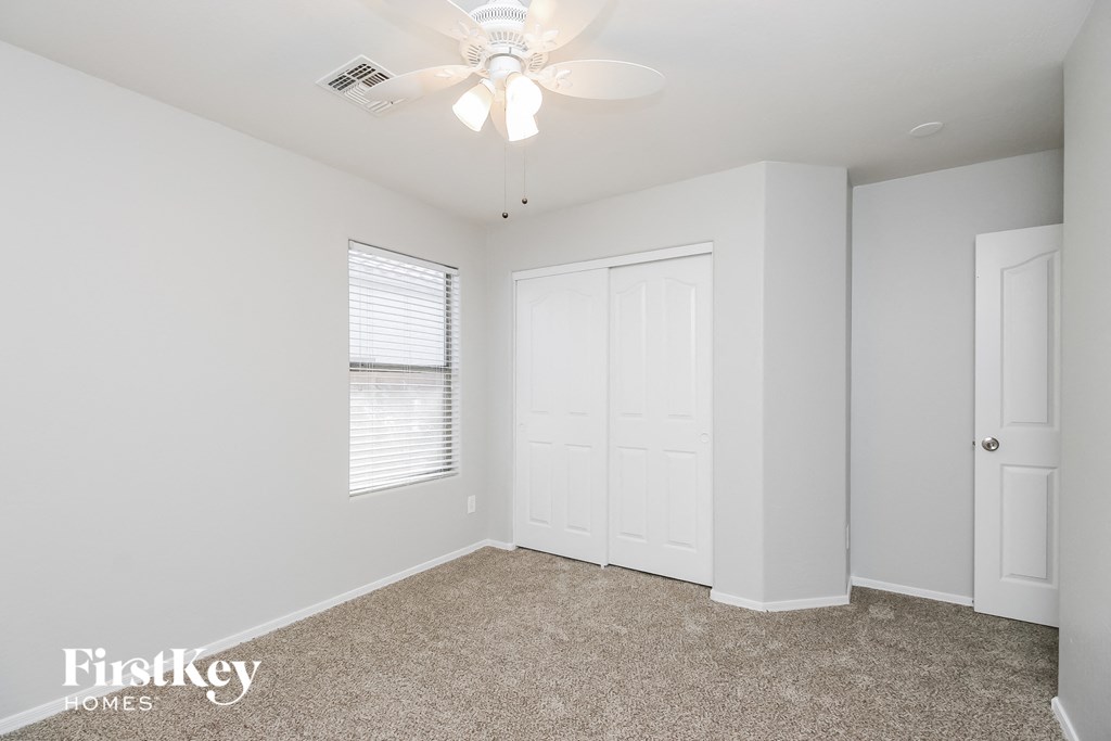 A room with a fan, carpet, and two doors.