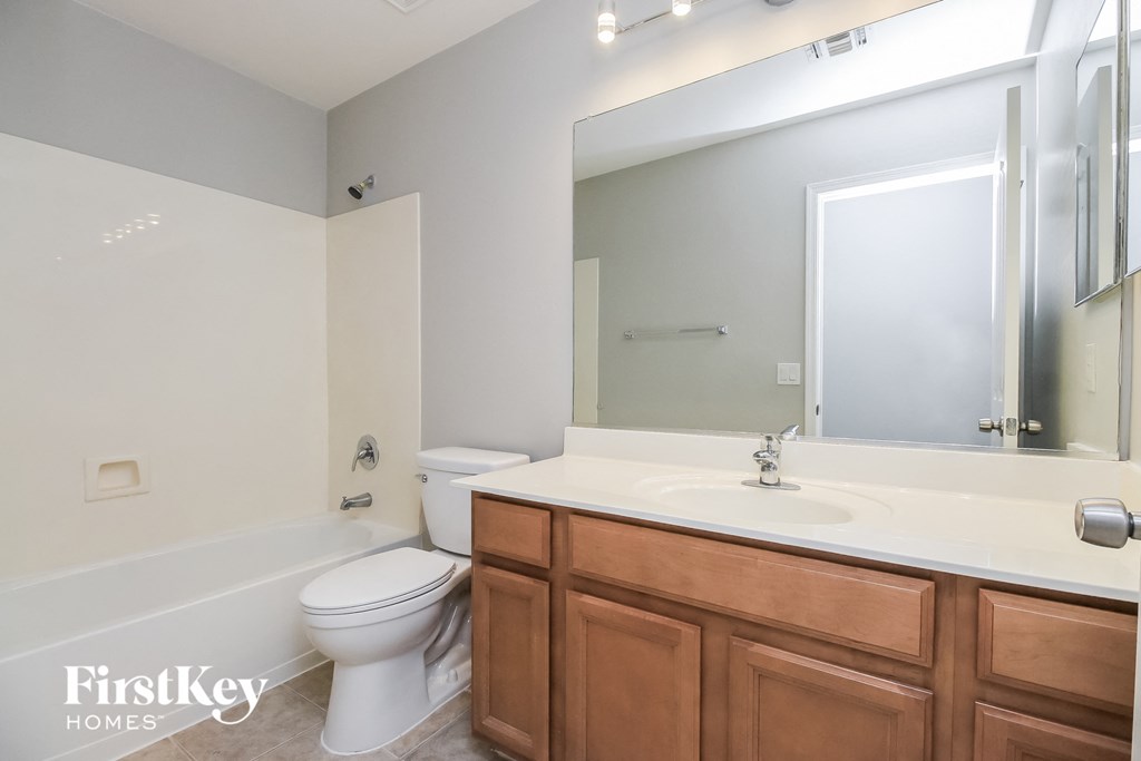 A bathroom with a white toilet and a wooden vanity.