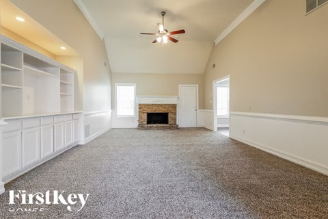 A spacious room with a fireplace and a ceiling fan.