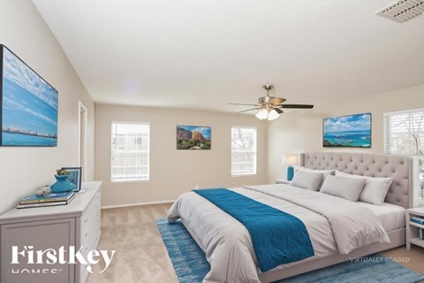 A bedroom with a large bed and a ceiling fan.