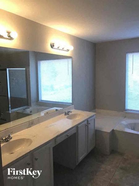 A bathroom with a tub, sink, and mirror.