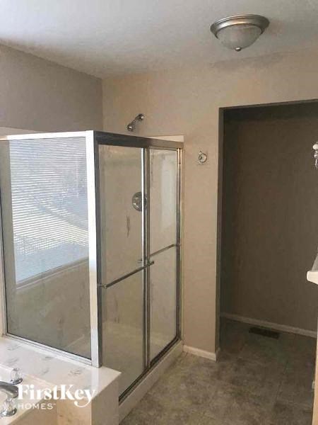 A glass shower stall with a white tub and a brown door.