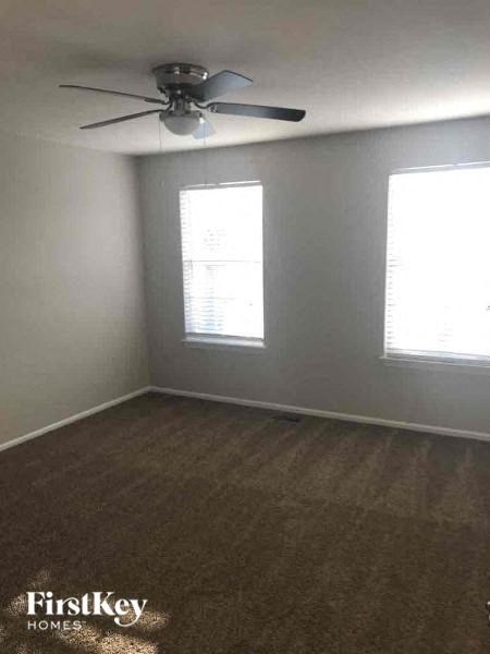 A room with a ceiling fan and two windows.