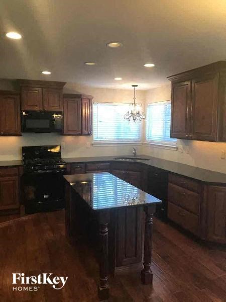 A kitchen with wooden cabinets and a black stove top oven.