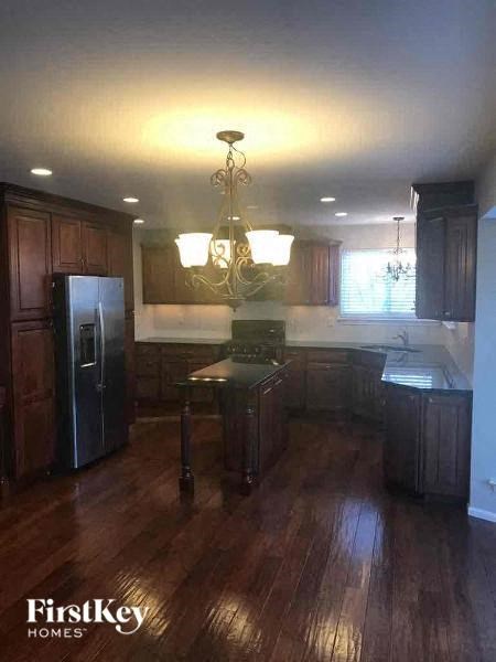 A kitchen with dark wood cabinets and a chandelier.