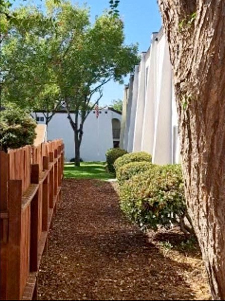 a walkway next to a building with trees and bushes