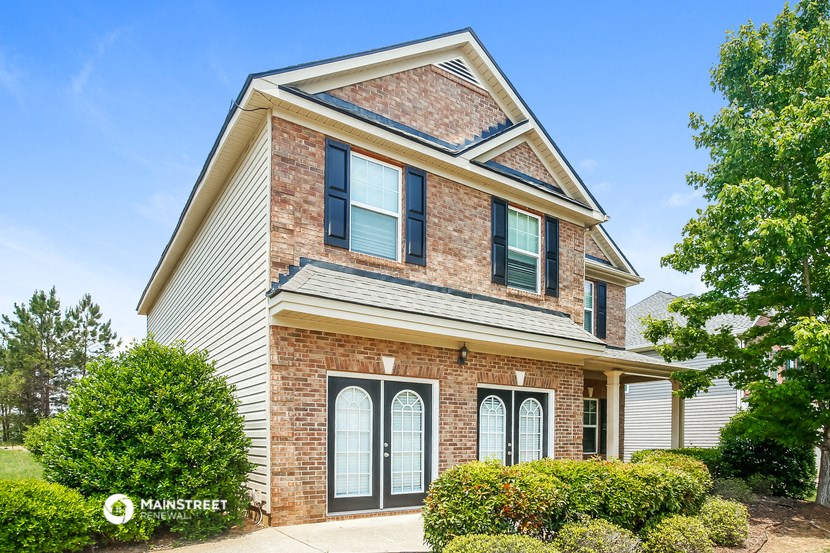 a brick house with white doors and green shutters