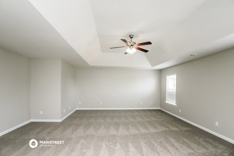 the spacious living room with ceiling fan and carpet