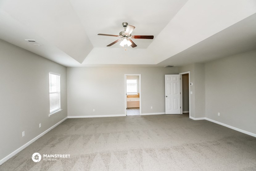 the spacious living room with ceiling fan and carpeting