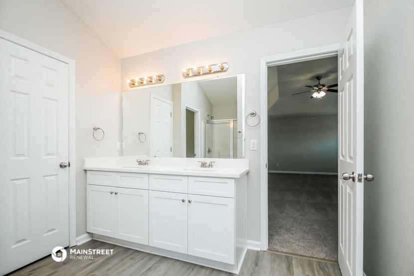 a bathroom with white cabinets and a large mirror